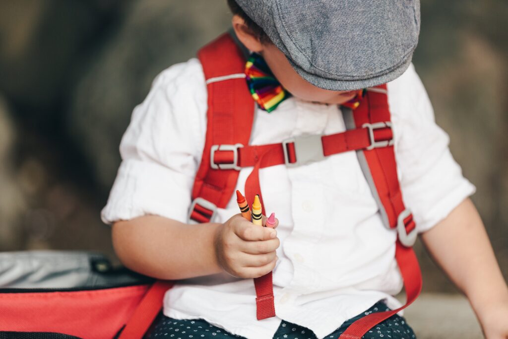 little-boy-in-hat-holding-crayons A little boy with a hat holding crayons in one hand