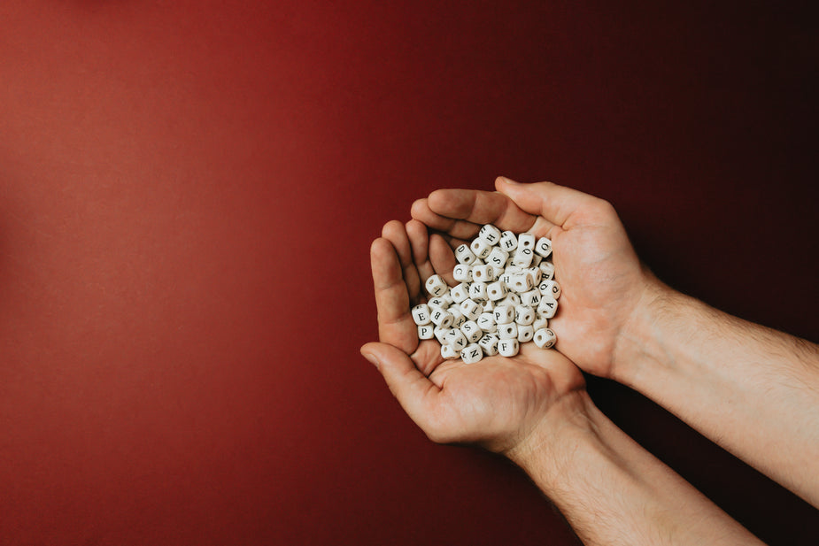 Hands holding beads with a variety of letters on them