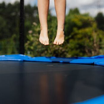 A child's bare feet captured mid-jump on a trampoline.