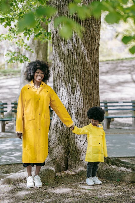 A joyful mother and child duo wearing matching yellow raincoats, enjoying a day outdoors.